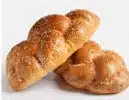 Two braided loaves of bread with a golden-brown crust, sprinkled lightly with sesame seeds, are placed on a white surface against a plain background.